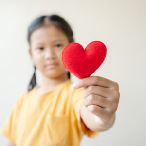 Selective focus on red heart shape Asian little girl showing love and hope concept