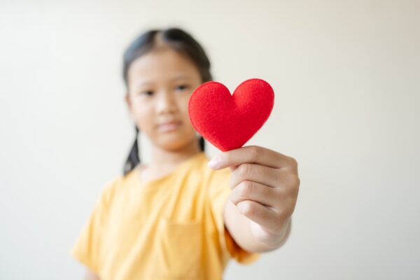 Selective focus on red heart shape Asian little girl showing love and hope concept